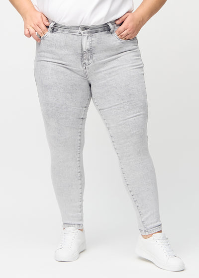 Lysegrå denim skinny jeans, modelnavn Ashes, som sidder tæt til benet på en plus-size model, set forfra.