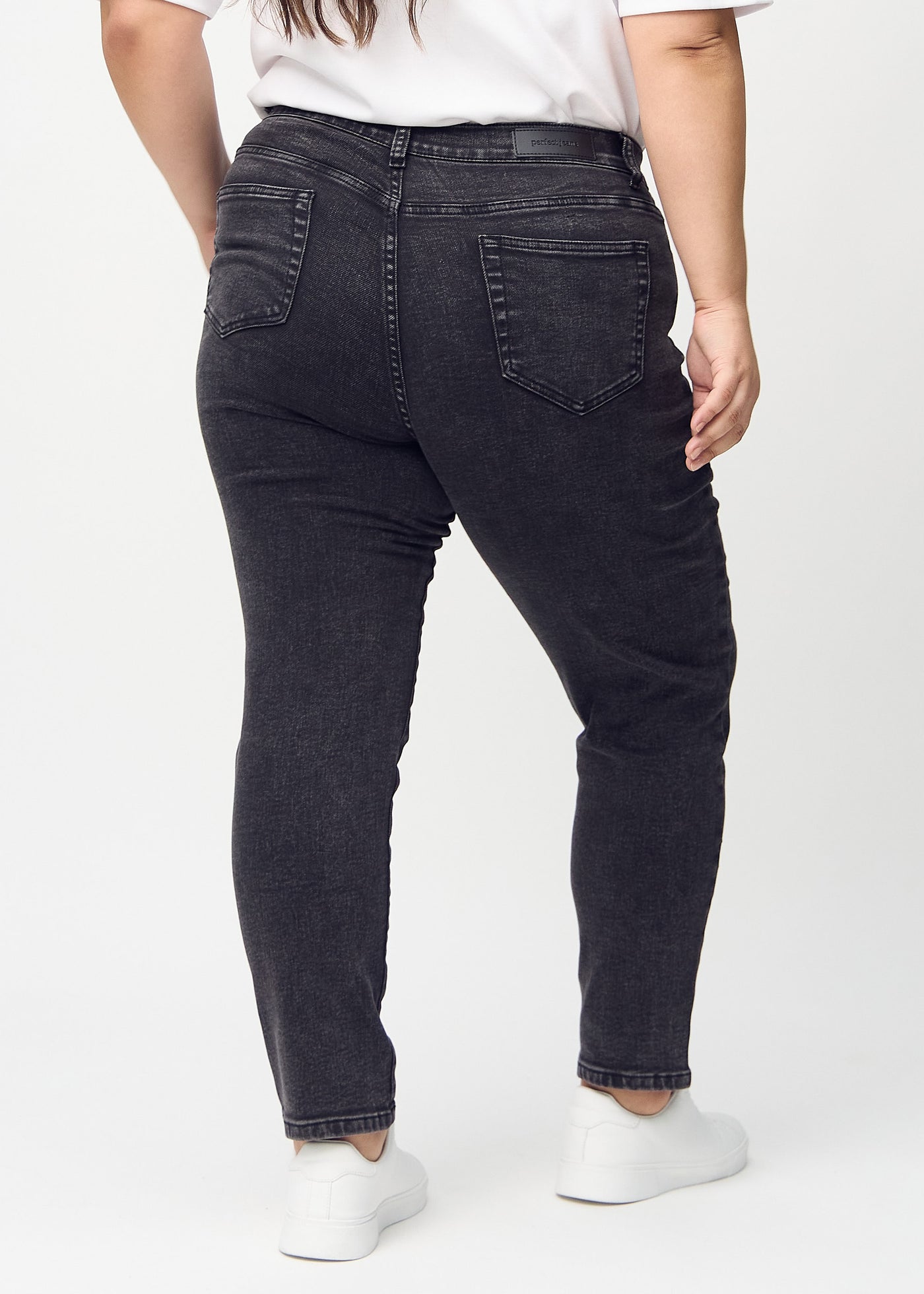 Mørkegrå denim slim jeans set bagfra på en plus-size model, så man kan se hele produktet.